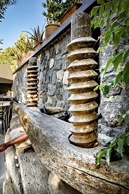 Ancient Basket Press next to a grey stone wall.